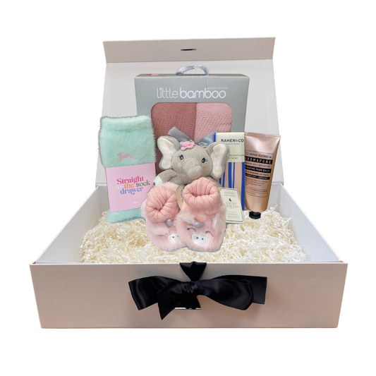 Baby girl gift set with plush toy, skincare products, booties and other items in a box.